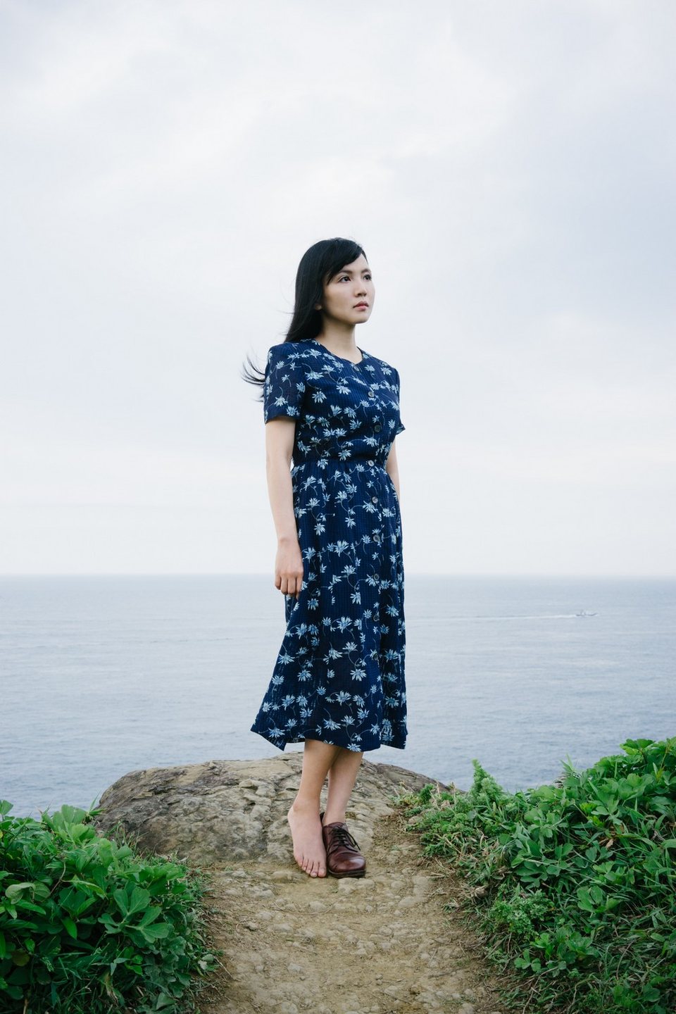 海岸遠景前穿藍色洋裝的女子肖像